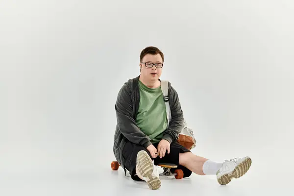 A happy young man with Down syndrome plays at home on a small skateboard. — Stock Photo