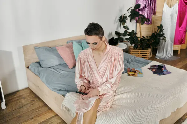 An attractive drag queen in pink attire checks their phone in a stylish bedroom. — Stock Photo