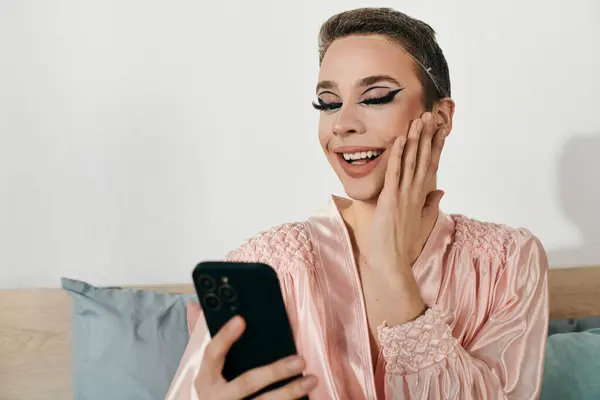 A young drag queen smiles brightly while posing with a smartphone. — Stock Photo