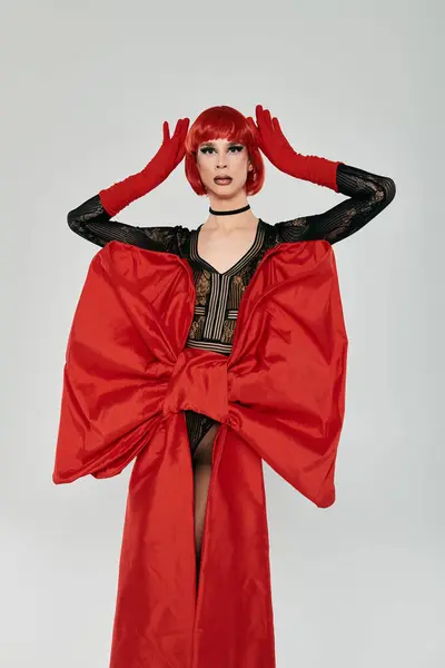 A attractive drag queen showcases a stunning red outfit and confident pose. — стоковое фото