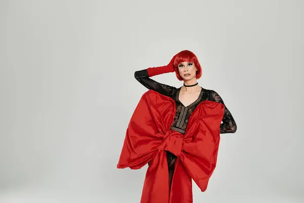 A striking drag queen showcases a dramatic red look with confidence and flair. — Stock Photo