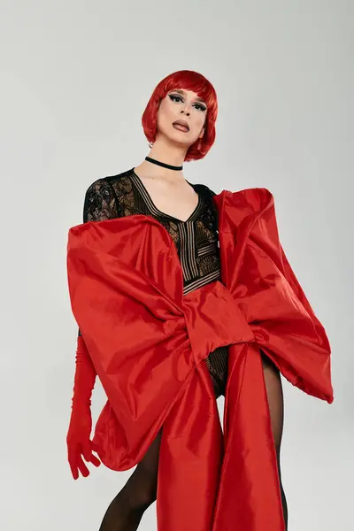 Une drag queen vibrante présente une superbe mode rouge dans une pose ludique. — Photo de stock