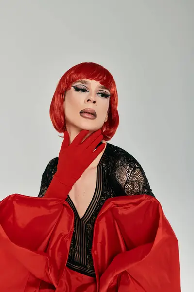 Una cautivadora drag queen exhibe un maquillaje vibrante y un llamativo atuendo rojo. - foto de stock