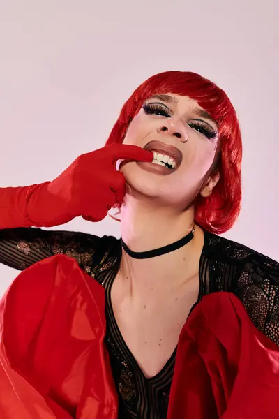An attractive drag queen expresses joy with a playful pose and striking red attire. — Stock Photo