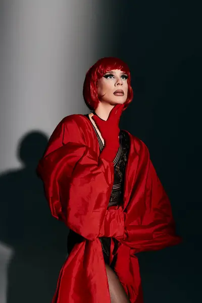 Una vibrante joven drag queen cautiva con una pose expresiva en llamativo atuendo rojo. - foto de stock