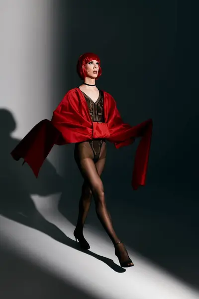 Une jeune drag queen respire la confiance tout en posant dans un ensemble rouge audacieux. — Photo de stock