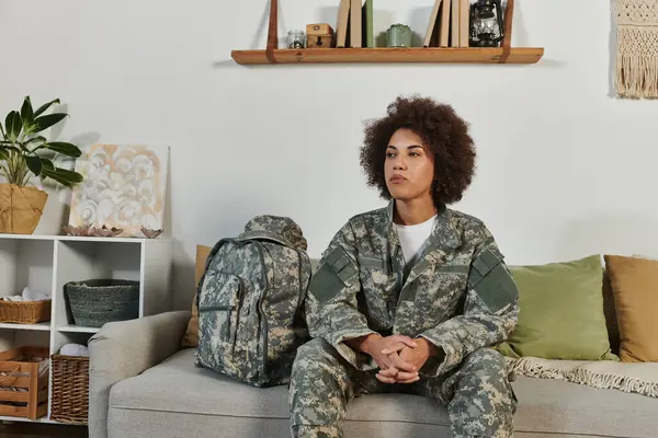 Uma jovem mulher de traje militar senta-se pensativa, pronta para embarcar em sua jornada de serviço em casa. — Fotografia de Stock