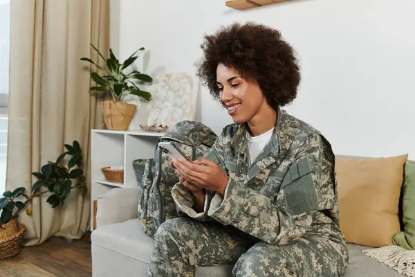 Uma jovem mulher de traje militar sorri enquanto se conecta com entes queridos antes de sua implantação. — Fotografia de Stock