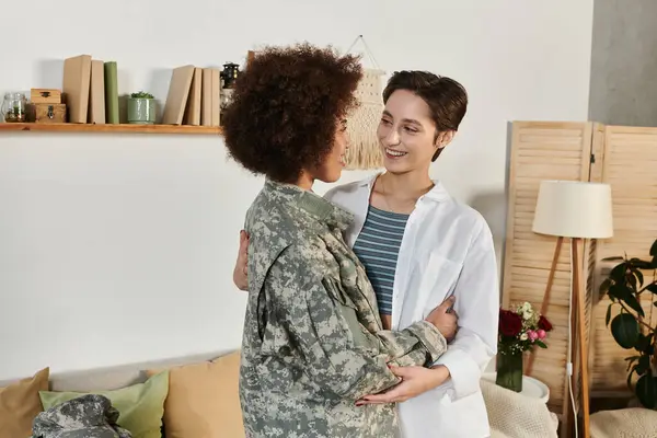 A soldier bids farewell to her loving wife in a cozy living room filled with warmth and affection. — Stock Photo
