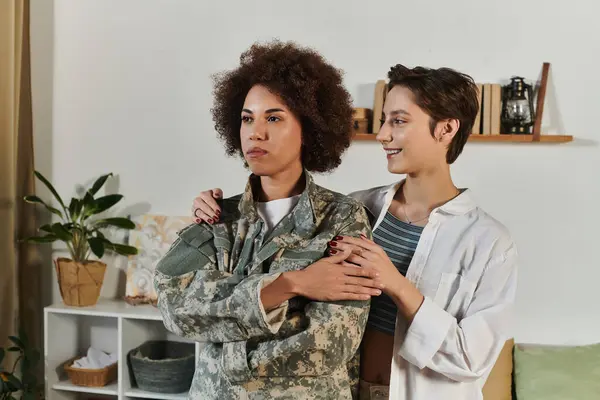 An emotional farewell as a service member hugs her wife in their cozy living room. — Stock Photo