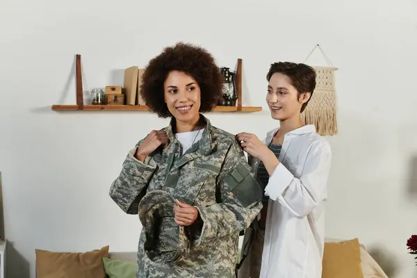 Un soldado se prepara para el servicio mientras su amante pareja ayuda con su uniforme, compartiendo un momento de corazón. — Stock Photo