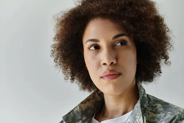 Una joven y fuerte afroamericana vestida de camuflaje irradia determinación y orgullo por su papel militar. - foto de stock