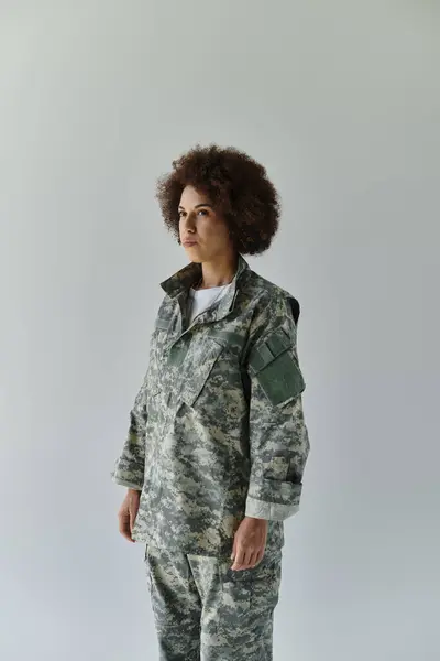 A confident young military woman in camouflage stands ready, showcasing her strength and dedication. — Stock Photo