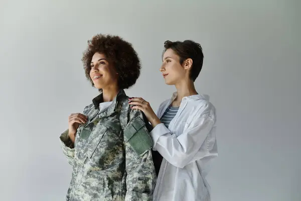 A soldier in camouflage uniform shares a tender moment with her wife in a studio space. — Stock Photo