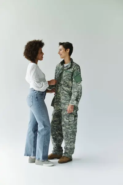A soldier prepares for deployment while sharing a tender moment with her wife. — Stock Photo