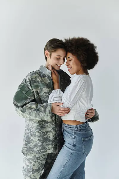 A young military soldier embraces her wife tenderly before deployment in a studio. — Stock Photo