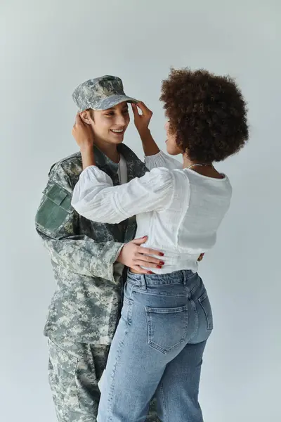 A loving farewell moment between a soldier and her wife in a warm studio atmosphere. — Stock Photo