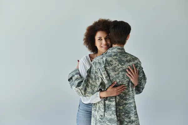 A soldier in camouflage uniform embraces her wife, capturing a moment of love and support before service. — Stock Photo