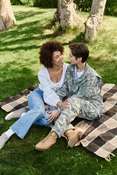 A soldier in uniform joyfully reunites with her wife in a peaceful park, sharing a heartfelt moment together. — Stock Photo