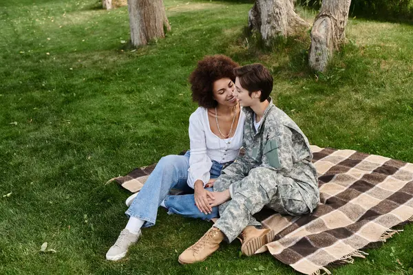 A joyous return as a soldier embraces her wife in a heartfelt reunion outdoors. — Stock Photo