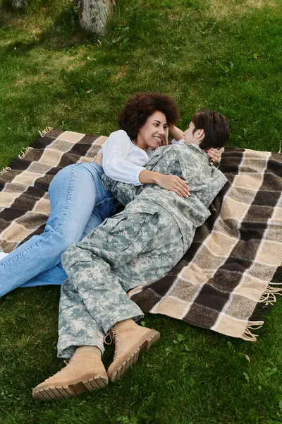 Un joven soldado es recibido alegremente por su esposa en una sincera reunión en un día soleado. — Stock Photo