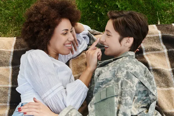 Un soldado abraza felizmente a su esposa al regresar a casa, compartiendo un momento alegre en un día soleado. — Stock Photo