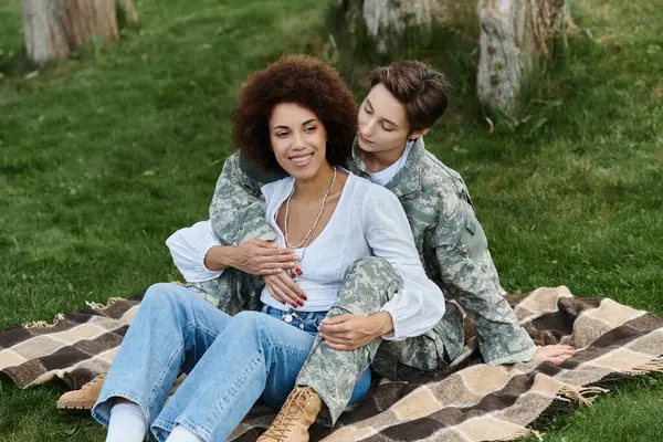 A joyful reunion unfolds as a soldier is warmly welcomed by her wife in a beautiful outdoor setting. — Stock Photo