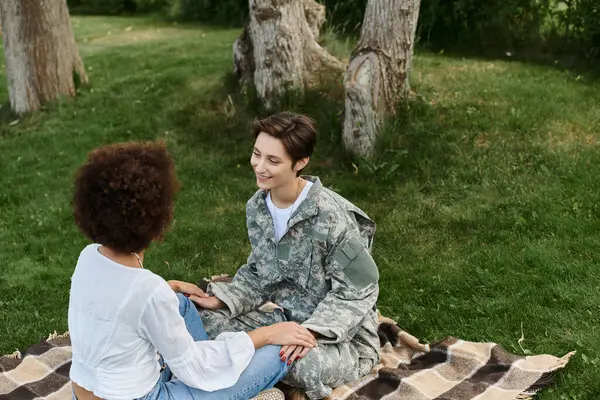 A joyful reunion unfolds as a soldier is greeted warmly by her loving wife in a peaceful park. — Stock Photo