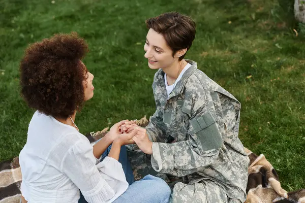 Una soldado en camuflaje comparte un momento sincero con su esposa al regresar a casa.. - foto de stock