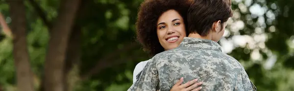 Un soldado se reúne alegremente con su esposa en una sincera bienvenida en medio de la naturaleza. - foto de stock