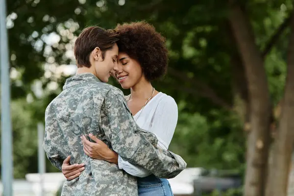 A military soldier joyfully reunites with her wife, embracing in a moment of love and relief. — Stock Photo