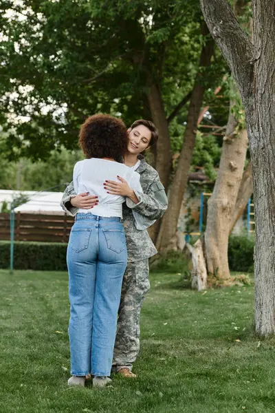 Una soldado se reúne alegremente con su esposa en un exuberante jardín, celebrando su amor y sacrificio. - foto de stock
