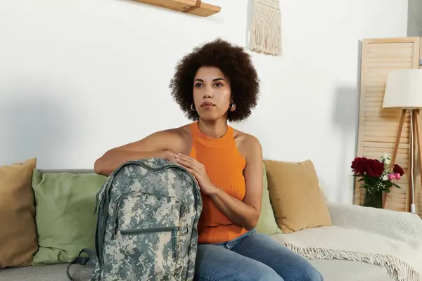 Thoughtful African american woman sitting on couch near her military backpack, servicewoman — Stock Photo