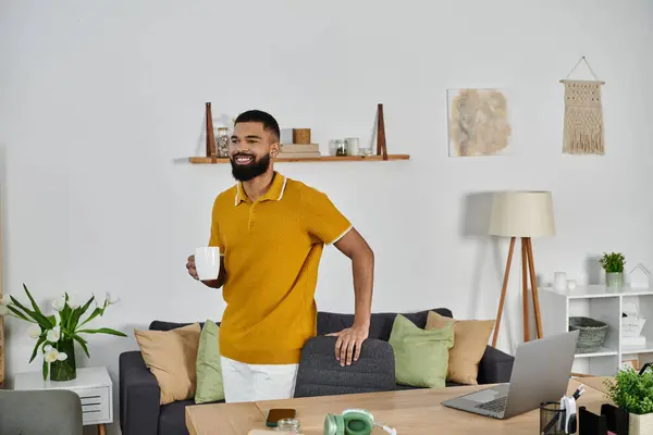 A cheerful man savors his coffee while standing at home. — Stock Photo