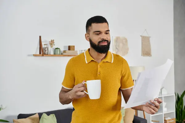 A man enjoys coffee while reviewing important documents in a warm setting. — Stock Photo