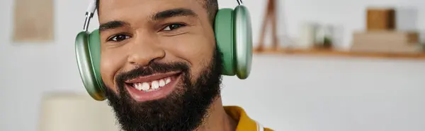 A cheerful man smiles while listening to music at home. — Stock Photo