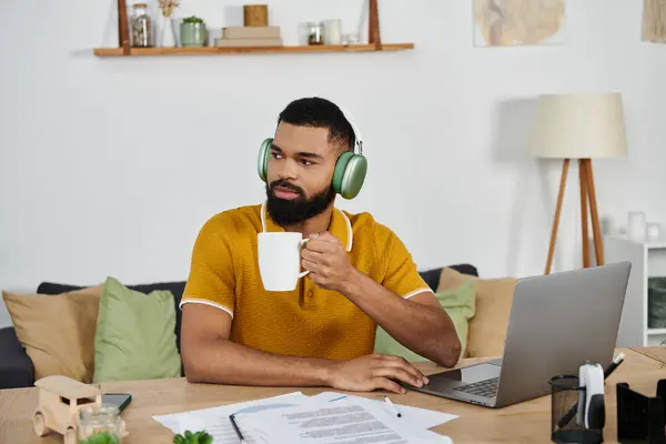 A stylish man sips coffee while focused on his laptop in a cozy environment. — Stock Photo