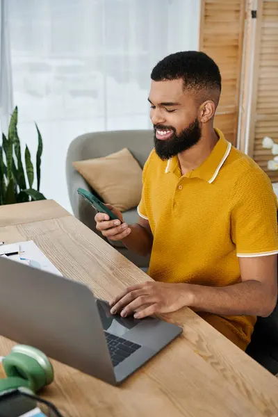 A young man relaxes at home, engaging with his smartphone and laptop. — Stock Photo