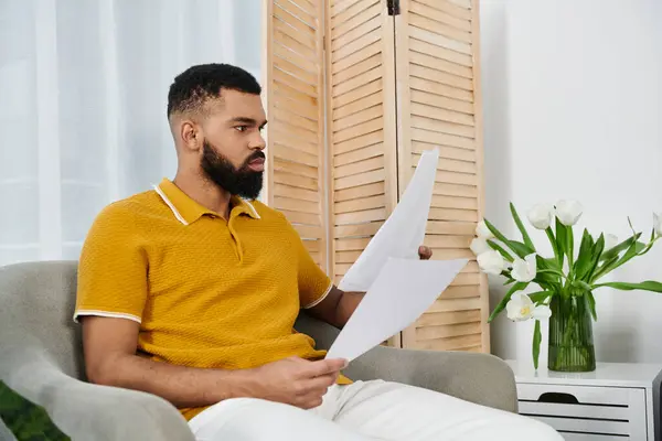 Man reflects thoughtfully at home surrounded by fresh flowers and soft sunlight. — Stock Photo