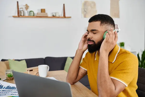A man enjoys music while relaxing at his cozy home workspace. — Stock Photo