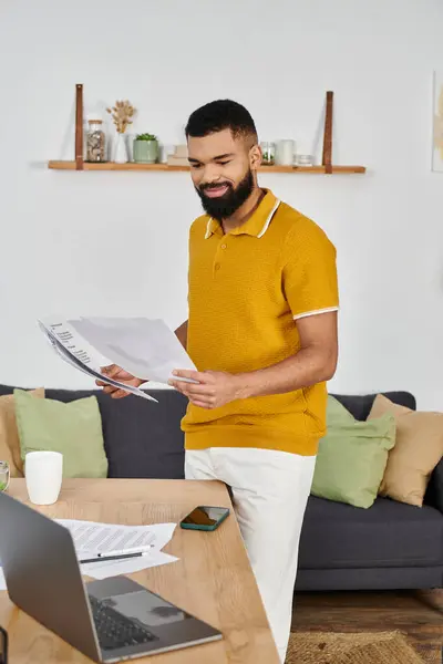 Ein stilvoller Mann überprüft seine Papiere, während er in einem gemütlichen Wohnzimmer einen Drink genießt. — Stockfoto