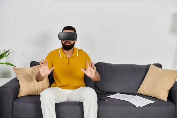 A man enjoys virtual reality while relaxing on his couch during the evening. — Stock Photo