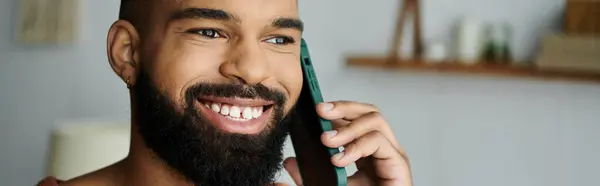 Un hombre alegre sonríe mientras charla por teléfono en su acogedor espacio de vida. — Stock Photo