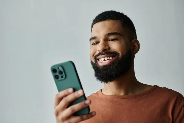 Cheerful man relaxes at home, captivated by his smartphone's content. — Stock Photo