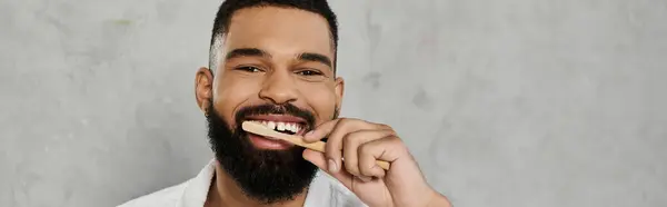 Um homem alegre escova os dentes enquanto sorri para a câmera. — Fotografia de Stock