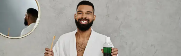 Smiling man holds toothbrush and mouthwash, radiating confidence in his home. — Stock Photo