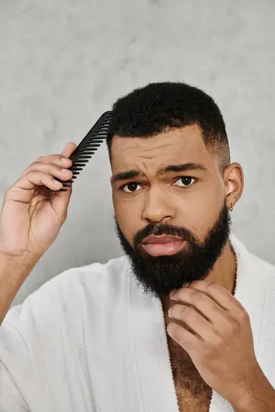 Ein Mann frisiert seine Haare nachdenklich, während er sich zu Hause entspannt. — Stockfoto