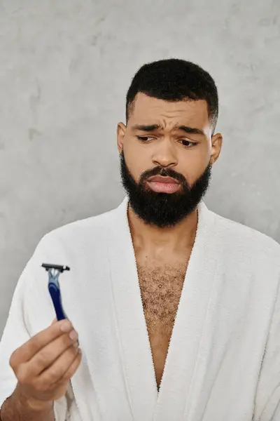 A thoughtful man examines his razor in a relaxed morning atmosphere. — Stock Photo