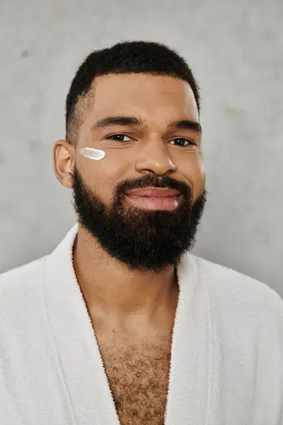 A man applies skincare while relaxing at home, embracing self care and wellness. — Stock Photo