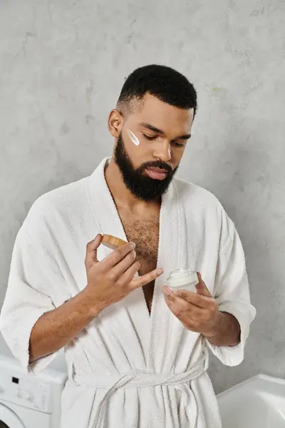 A man enjoys self care, applying cream while relaxed at home. — Stock Photo